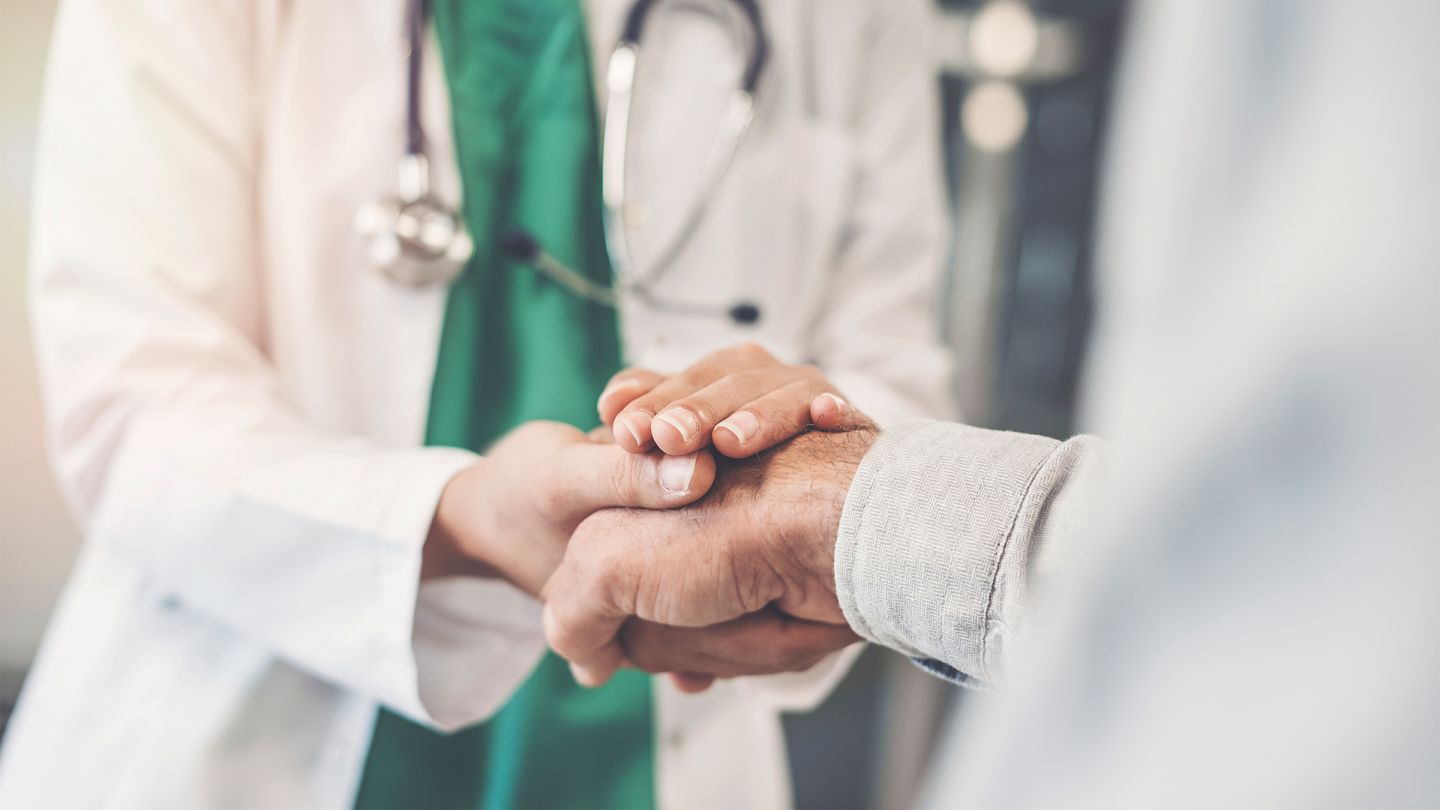 Patient mit Bauchspeicheldrüsenentzündung (Quelle: Getty Images/seb_ra) Bauchspeicheldrüsenentzündung: Ein Arzt umschließ mit beiden Händen die Hand eines Patienten.