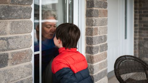 Großmutter und Enkel (Quelle: Getty Images/Cavan Images) Eine ältere Frau und ein Junge stehen sich nah gegenüber - getrennt durch ein Fenster. Die Frau befindet sich in der Wohnung, der Junge draußen. Beide nähern ihre Gesichter der Fensterscheibe, die Frau deutet einen Kuss an..