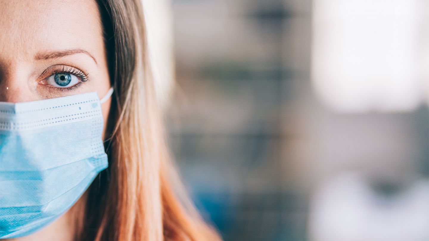 COVID-19 (Symbolbild) (Quelle: iStock/valentinrussanov) Covid-19 und psychische Gesundheit: Eine junge Frau schaut in die Kamera. Sie trägt einen medizinischen Mund-Nase-Schutz.