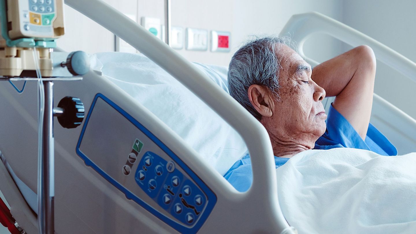 Mann im Krankenhaus (Quelle: Getty Images/ponsulak) Dekubitus: Ein älterer Mann liegt mit geschlossenen Augen in einem Krankenhausbett.