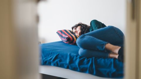 Depression Symptome (Symbolbild) (Quelle: Getty Images/recep-bg) Eine depressiv wirkende Frau liegt auf einem Bett und blickt ins Leere.