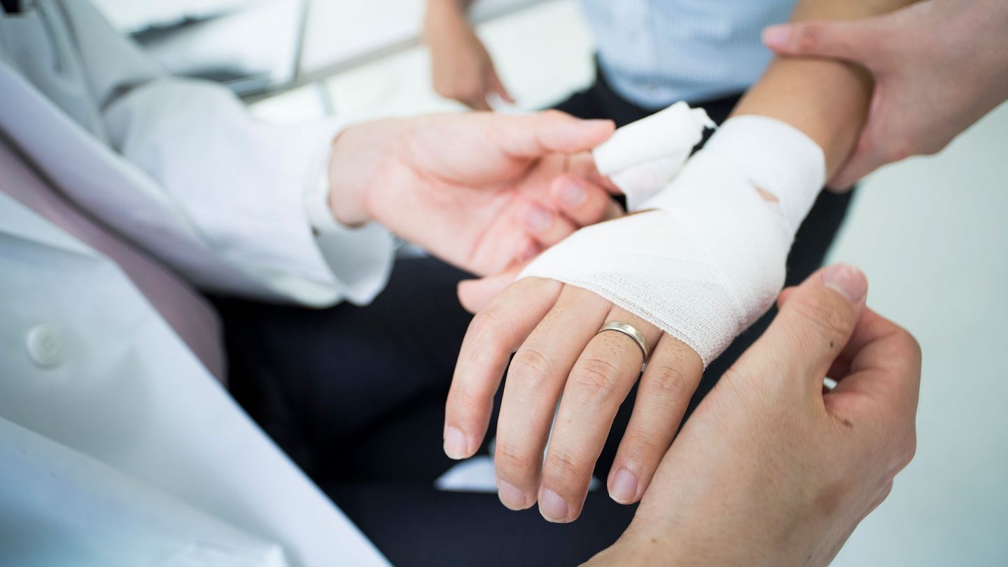 Wundverband bei Erysipel (Quelle: Getty Images/kokouu) Erysipel: Ein Mann erhält einen Verband ums Handgelenk.