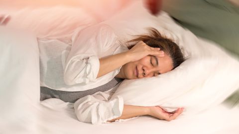 Hirntumore Symptome (Quelle: Getty Images/Pornpak Khunatorn) Eine Frau liegt im Bett und fasst sich mit der rechten Hand an ihre Schläfe. Ihre Augen sind geschlossen und ihr Gesicht ist angespannt.