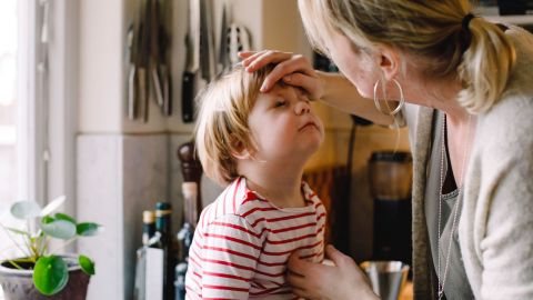 Fremdkörper im Auge: Mutter und Sohn (Quelle: Getty Images/Maskot) Hornhautnarben und Hornhauttrübungen: Eine Frau steht vor einem kleinen Jungen und berührt ihn mit einer Hand an der Stirn. Dabei schaut sie dem Jungen in ein Auge.