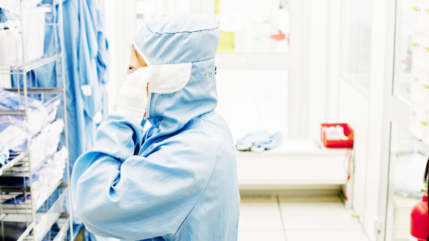 Milzbrand (Quelle: iStock/FroggyFrogg) Milzbrand: Eine Person, die von Kopf bis Fuß in einem Schutzanzug steckt, steht in einem Labor vor einem Regal.