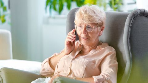 Frau bei telefonischer Beratung (Quelle: Getty Images/izusek) Eine Frau mittleren Alters lehnt in einem großen Sessel. Mit der rechten Hand hält sie sich ein mobiles Telefon ans Ohr.