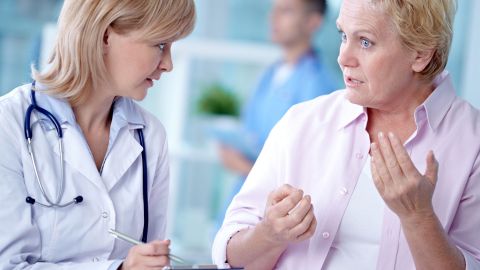 Gespräch zwischen Ärztin und Patientin (Symbolbild) (Quelle: Getty Images/mediaphotos) Beschwerde über ärztliche Behandlung: Eine Ärztin und eine Frau stehen sich gegenüber. Die Frau, womöglich eine Patientin oder Angehörige, hält gestikulierend beide Hände vor die eigene Brust und redet. Die Ärztin schaut sie an.