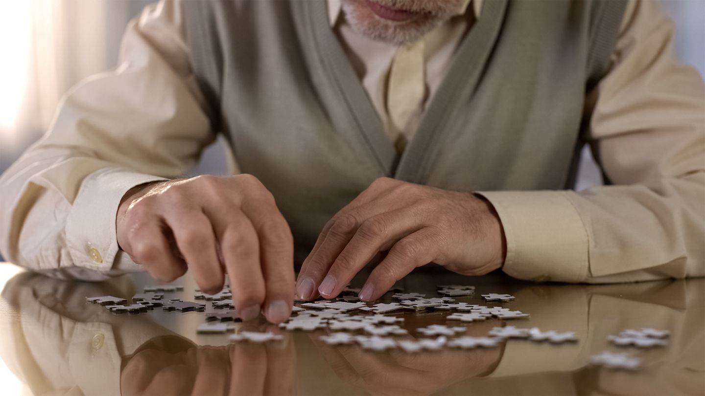 Vaskuläre Demenz (Quelle: Getty Images/Motortion) Ein älterer Herr sitzt an einem Tisch und puzzelt.