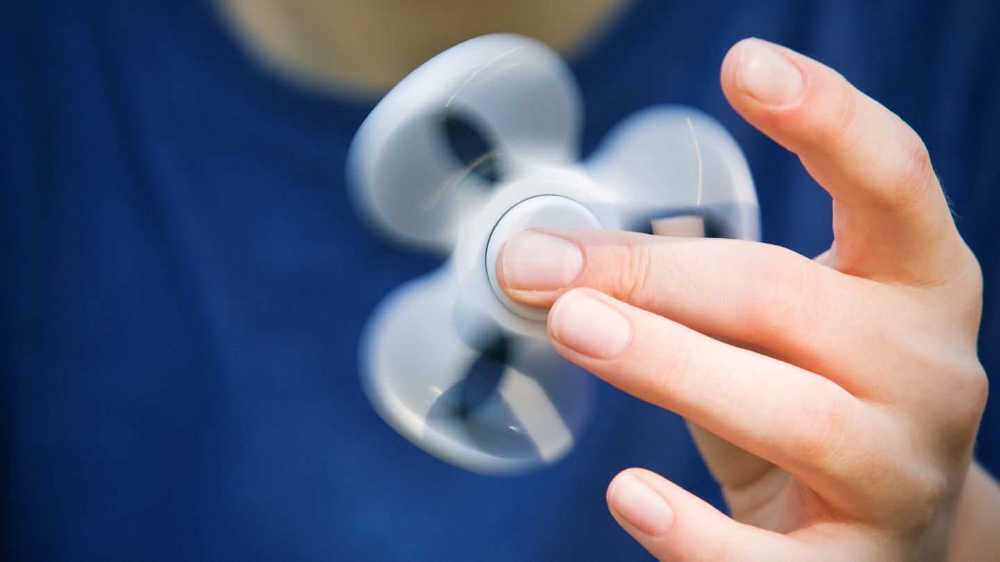 Handkreisel (Fidget Spinner) (Quelle: Getty Images/sdominick) ADHS: Finger wirbeln einen Handkreisel (Fidget Spinner) umher.