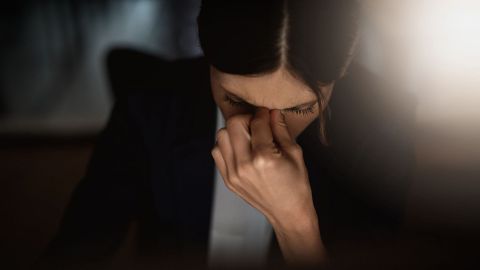 Burn-out-Syndrom (Quelle: Getty Images/PeopleImages) Burn-out: Eine Frau mit gesenktem Kopf fasst sich zwischen Nase und Stirn.
