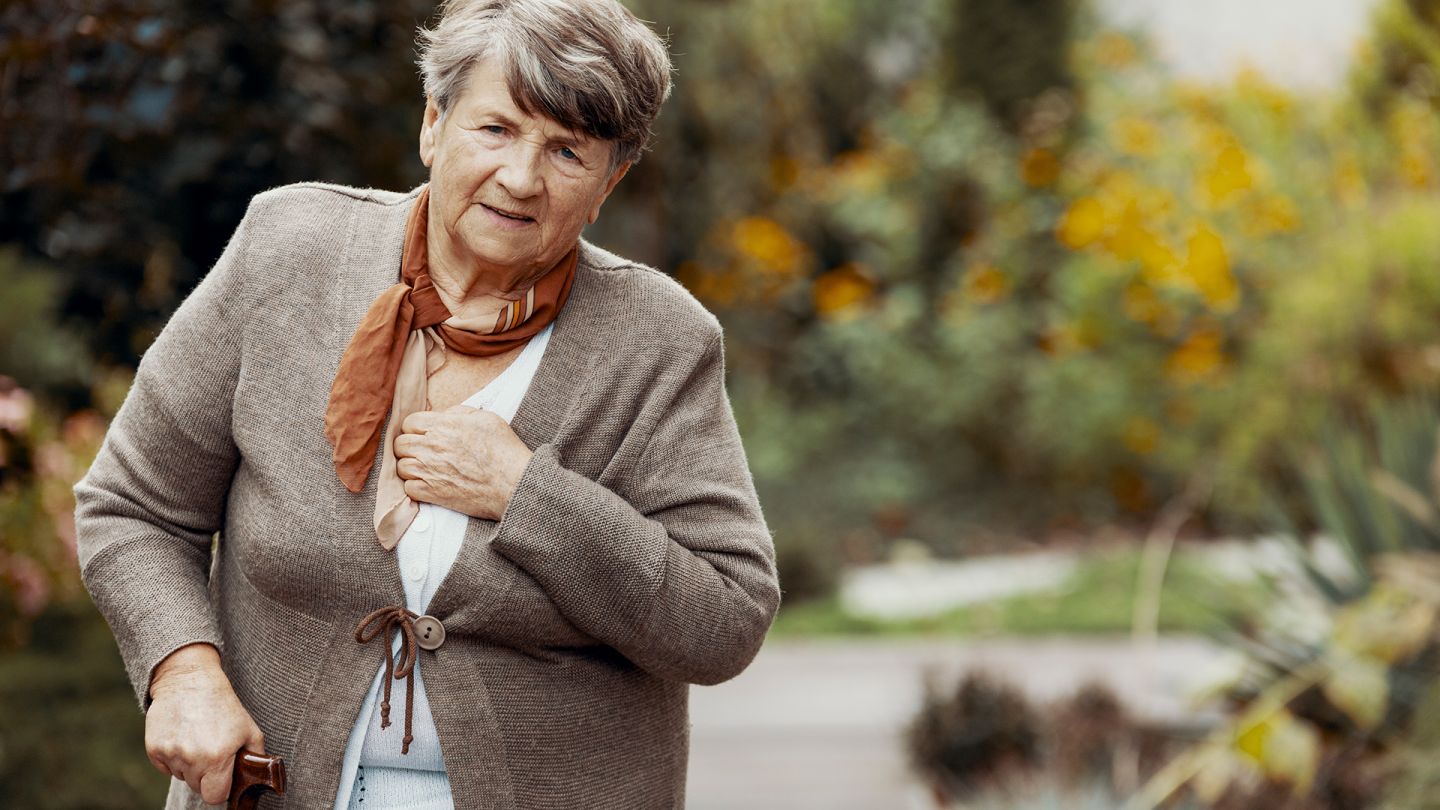Chronisch-obstruktive Lungenerkrankung (COPD) (Symbolbild) (Quelle: Getty Images/KatarzynaBialasiewicz) Chronisch-obstruktive Lungenerkrankung: Eine ältere Frau fasst sich an den Brustkorb. In der anderen Hand hält sie einen Gehstock.