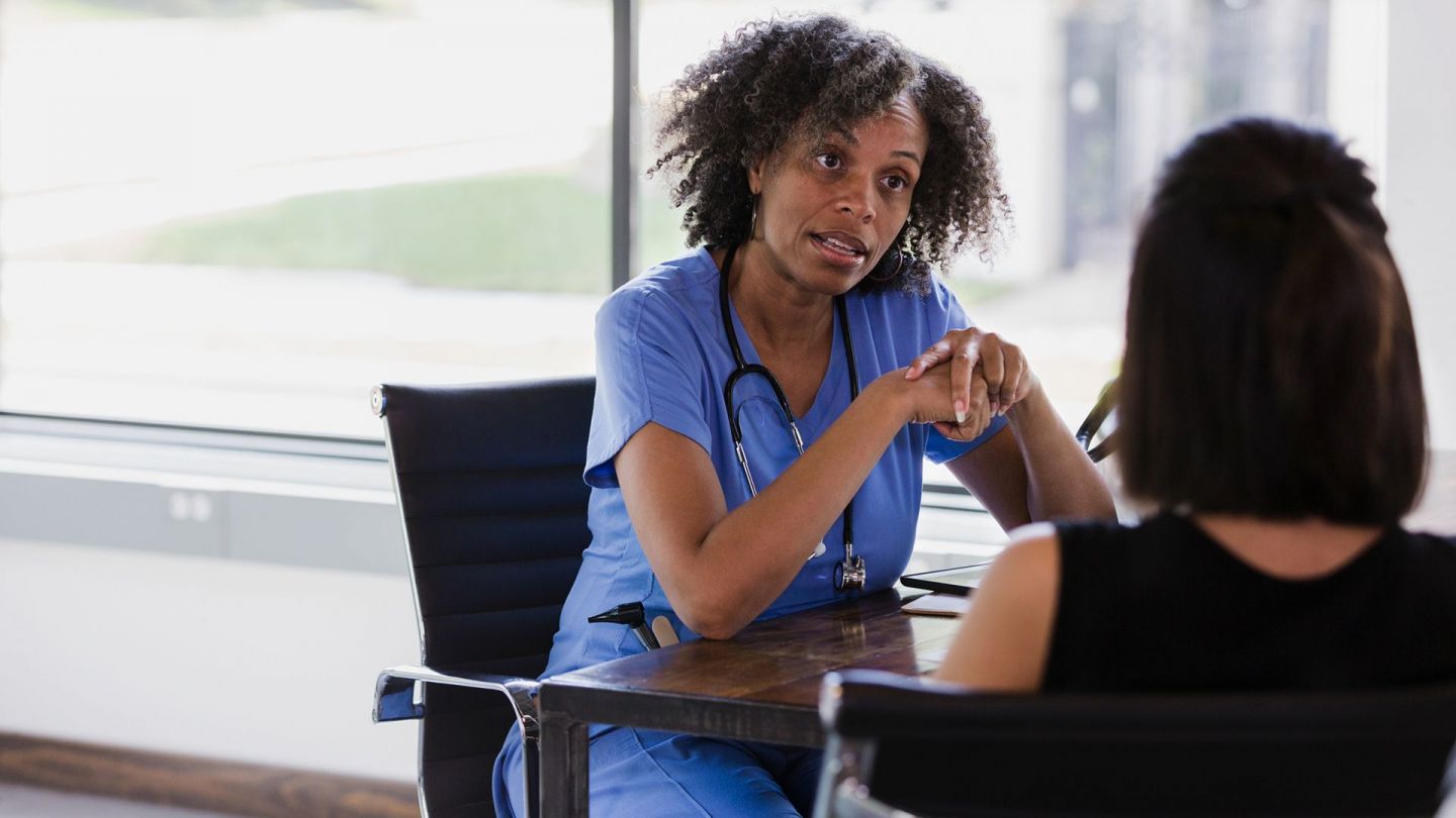 Gespräch mit Patientin (Symbolbild) (Quelle: Getty Images/SDI Productions) Eierstockkrebs: Eine Ärztin und eine Patientin sitzen an einem Tisch. Die Ärztin spricht mit der Patientin.