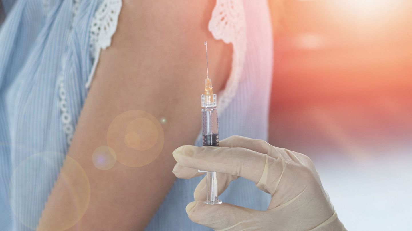 Spritze (Quelle: Getty Images/Pornpak Khunatorn) Gebärmutterhalskrebs: Eine Hand hält eine aufgezogene Spritze. Im Hintergrund ist der Arm einer Frau zu sehen.