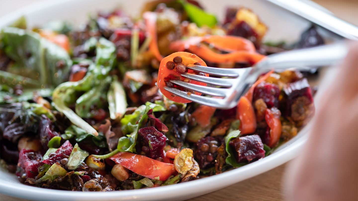 Gesunde Ernährung (Quelle: Getty Images/PamelaJoeMcFarlane) Gesund durch Ernährung: Eine Person piekt mit einer Gabel in einen bunten Salat mit Linsen.