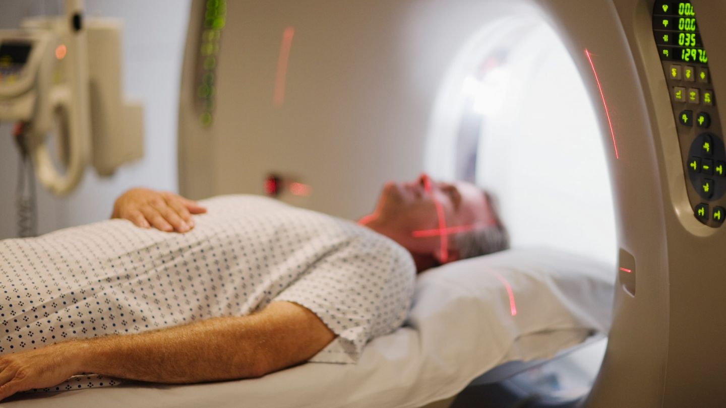 Patient in MRT-Röhre (Symbolbild) (Quelle: Getty Images/Fuse) Multiples Myelom: Ein Mann liegt in einer MRT-Röhre. Über seinem Gesicht verlaufen zwei rote Laser.
